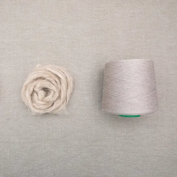 Basket 100% hemp curtain fabric with natural beige color, soft flowing linen-look texture, loosely woven sustainable and biodegradable hemp material shown with yarn ball and thread spool.