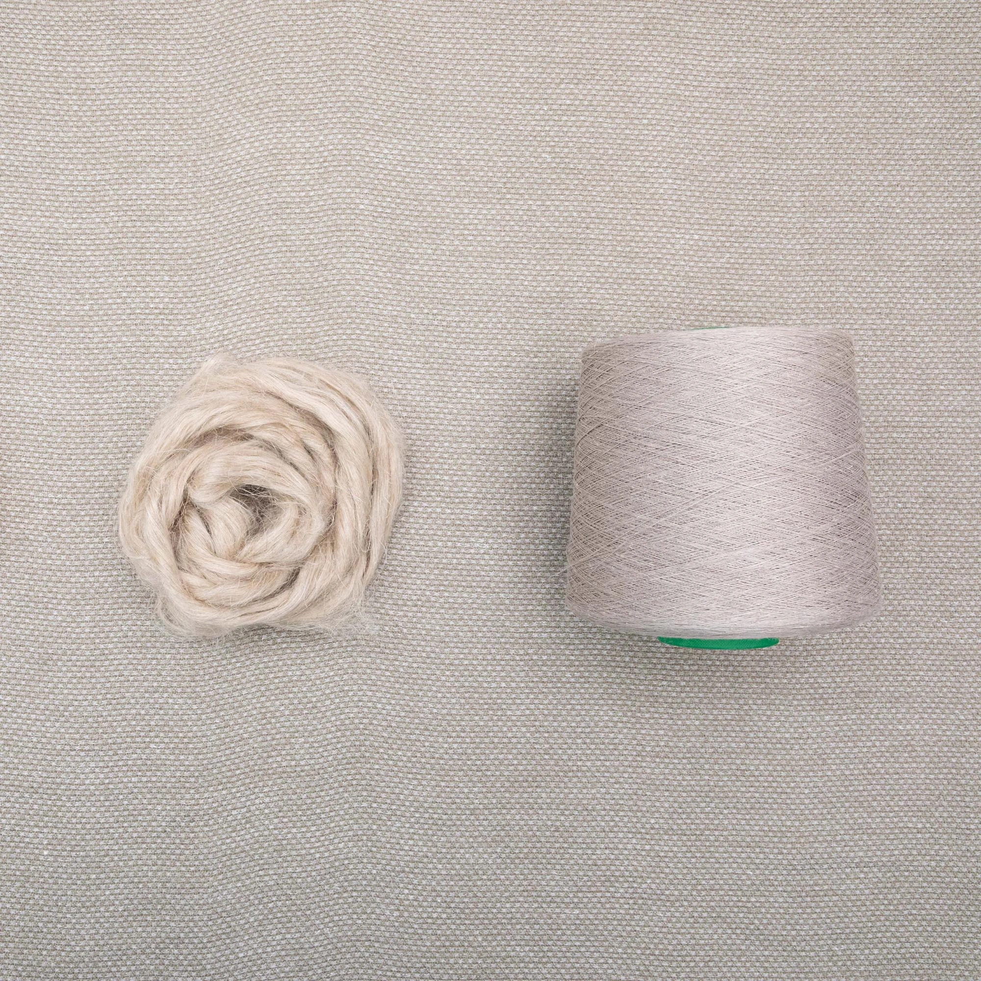 Basket 100% hemp curtain fabric with natural beige color, soft flowing linen-look texture, loosely woven sustainable and biodegradable hemp material shown with yarn ball and thread spool.