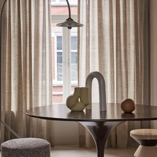 Dew sheer curtain fabric in a soft natural tone, made from 90% wool and 10% linen, shown as inbetween transparent drapery that gently filters daylight in an elegant interior, OEKOTEX certified.