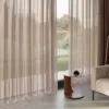 Ebben room-high sheer curtain fabric with subtle two-tone effect, made from 100% polyester, shown as inbetween transparent drapery in a calm modern living room with floor-to-ceiling windows, soft neutral interiors, and natural daylight filtering through the fabric, OEKOTEX certified.