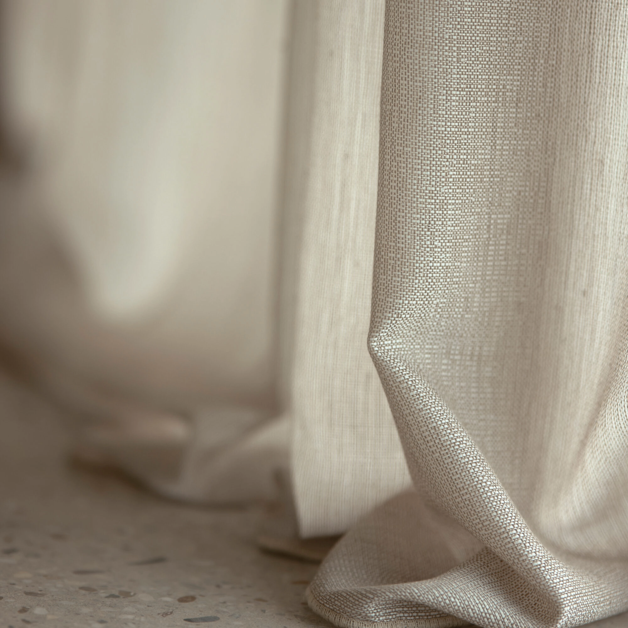Flow in-between curtain fabric with soft satin-like sheen, made from 100% recycled Trevira CS polyester, shown in a close-up drape with subtle irregular weave, light-filtering transparency, room-high and flame-retardant, OEKOTEX certified.