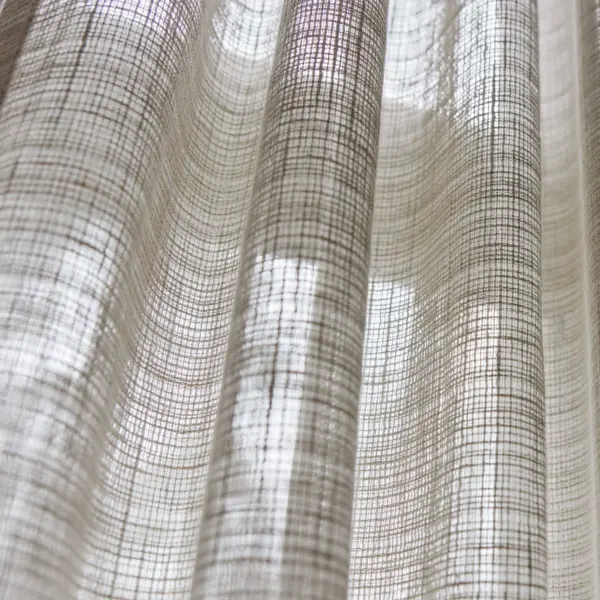 Gerst sheer curtain fabric close-up showing an inbetween transparent open weave, made from a blend of polyester, cotton, linen, and viscose, featuring a natural grid texture that softly filters daylight, OEKOTEX certified.
