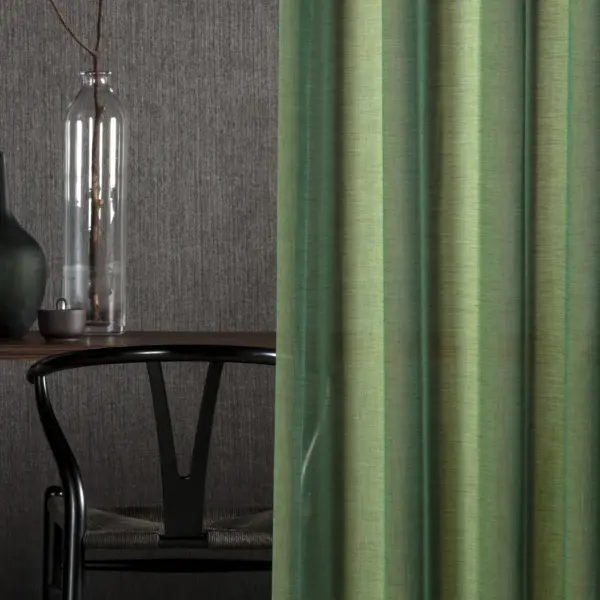 Mizu sheer curtain fabric close-up with a colorfully woven inbetween transparent texture, made from 100% Trevira CS polyester, featuring a soft natural feel with subtle shimmer and shifting yarn colors inspired by water, OEKOTEX certified.