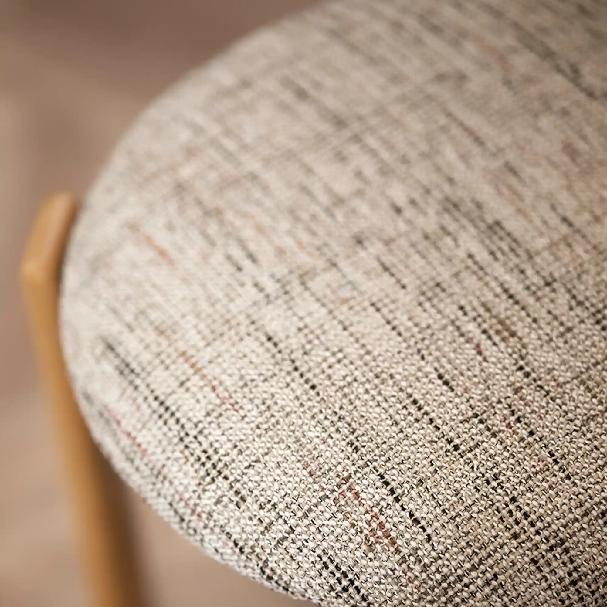 Nubis upholstery fabric with a tweed-effect woven texture, made from a multi-material blend including polyester, acrylic, cotton, and wool, shown upholstered on a chair in a warm modern interior with natural wood accents, highlighting its vintage-inspired character.