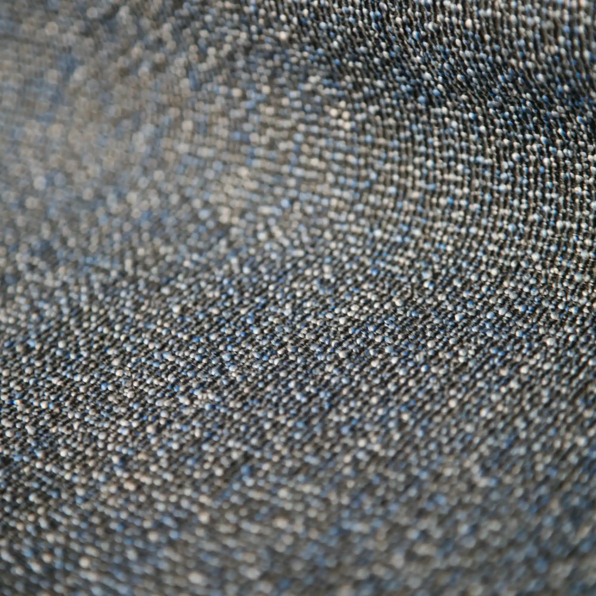 Reno upholstery fabric close-up with a sturdy woven structure and subtle melange color effect, made from a durable blend of polyester and cotton, featuring a three-dimensional texture created by contrasting warp and weft yarns, suitable for modern residential and commercial furniture interiors.